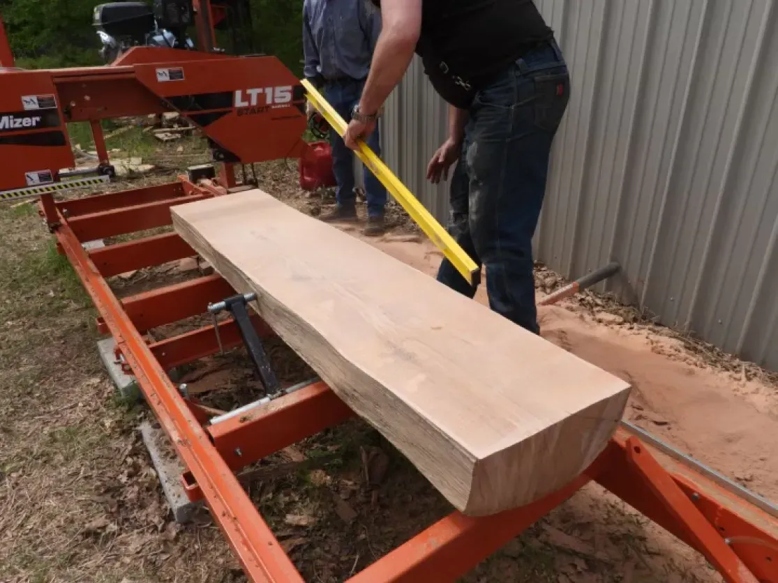 A man is measuring a piece of wood on a machine that says lt15