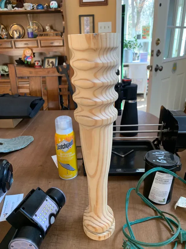 A wooden object is sitting on a table next to a spray bottle.