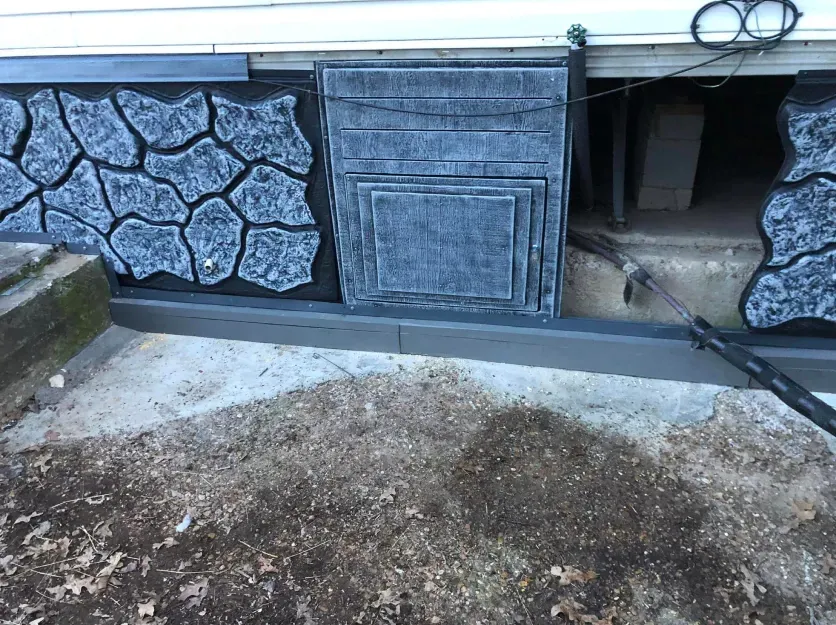 A stone wall is being painted on the side of a house.