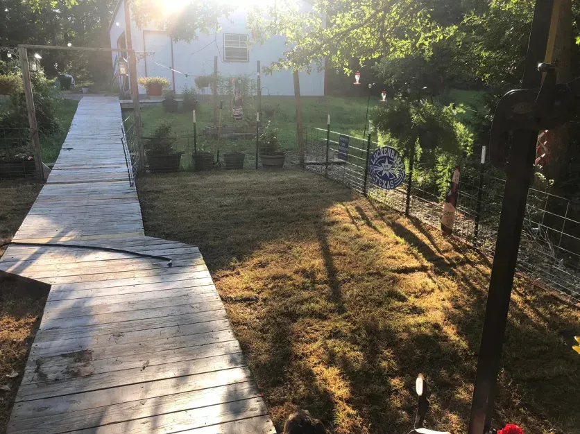 A wooden walkway leading to a house in the backyard.