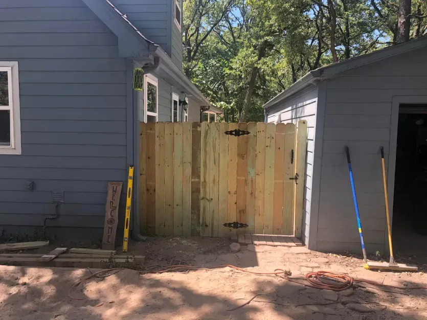 A wooden fence is being built in front of a house.