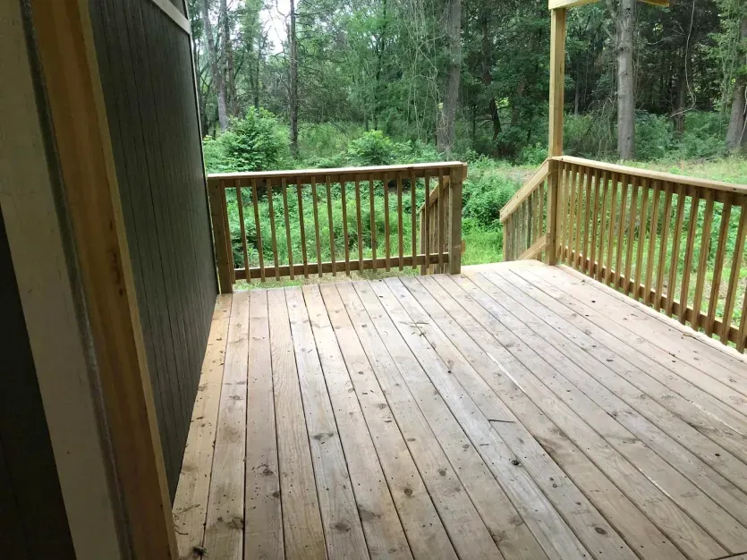 A wooden deck with a railing and trees in the background