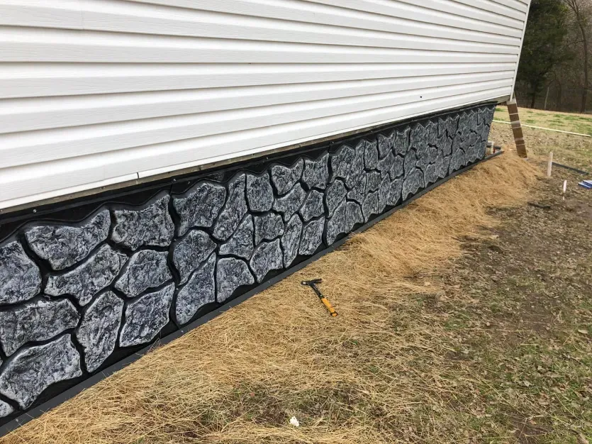 The side of a house with a stone wall painted on it.