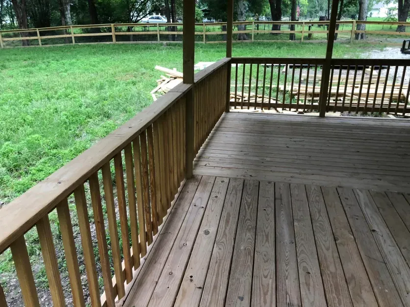 An empty wooden deck with a fence in the background