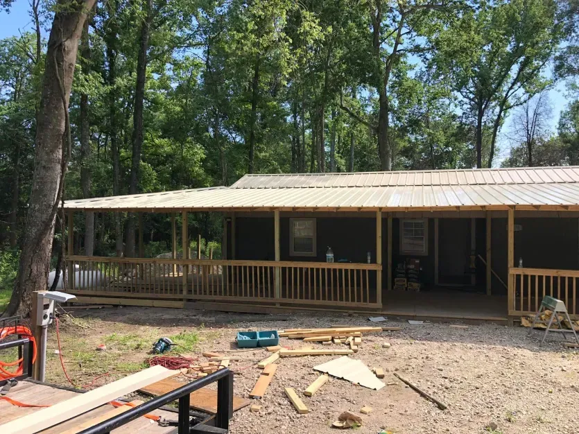 A house with a porch is being built in the woods.
