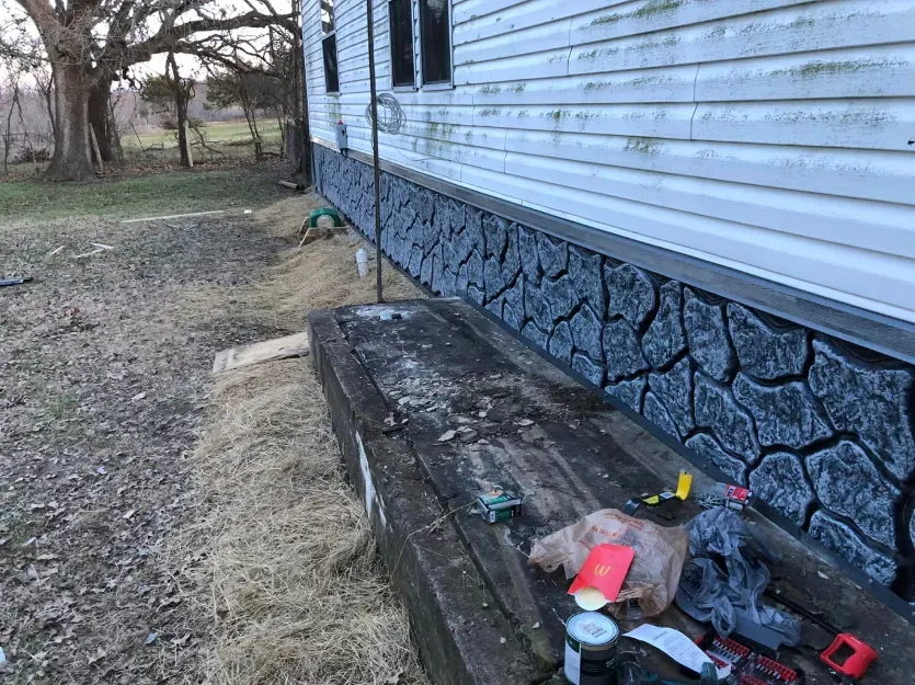 A wooden bench is sitting in front of a house that is being painted.