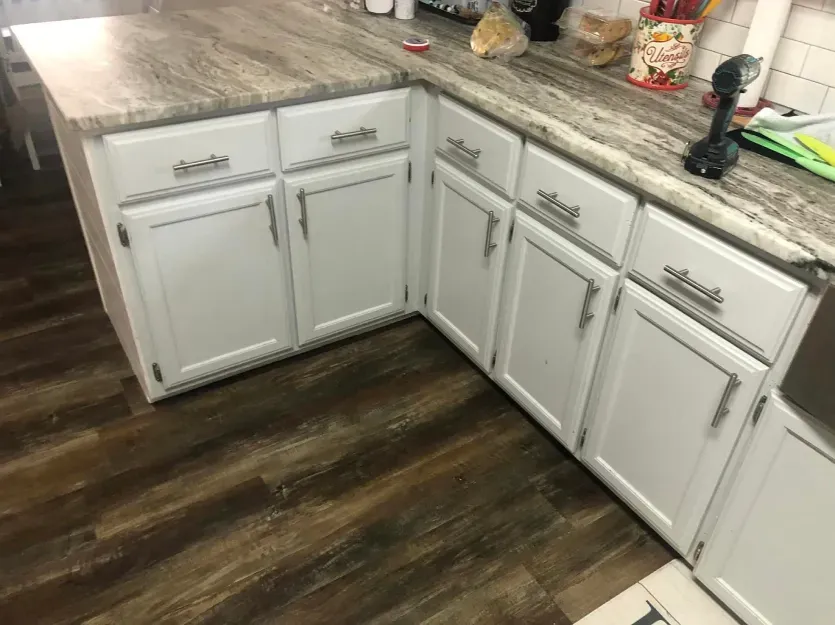 A kitchen with white cabinets and granite counter tops.