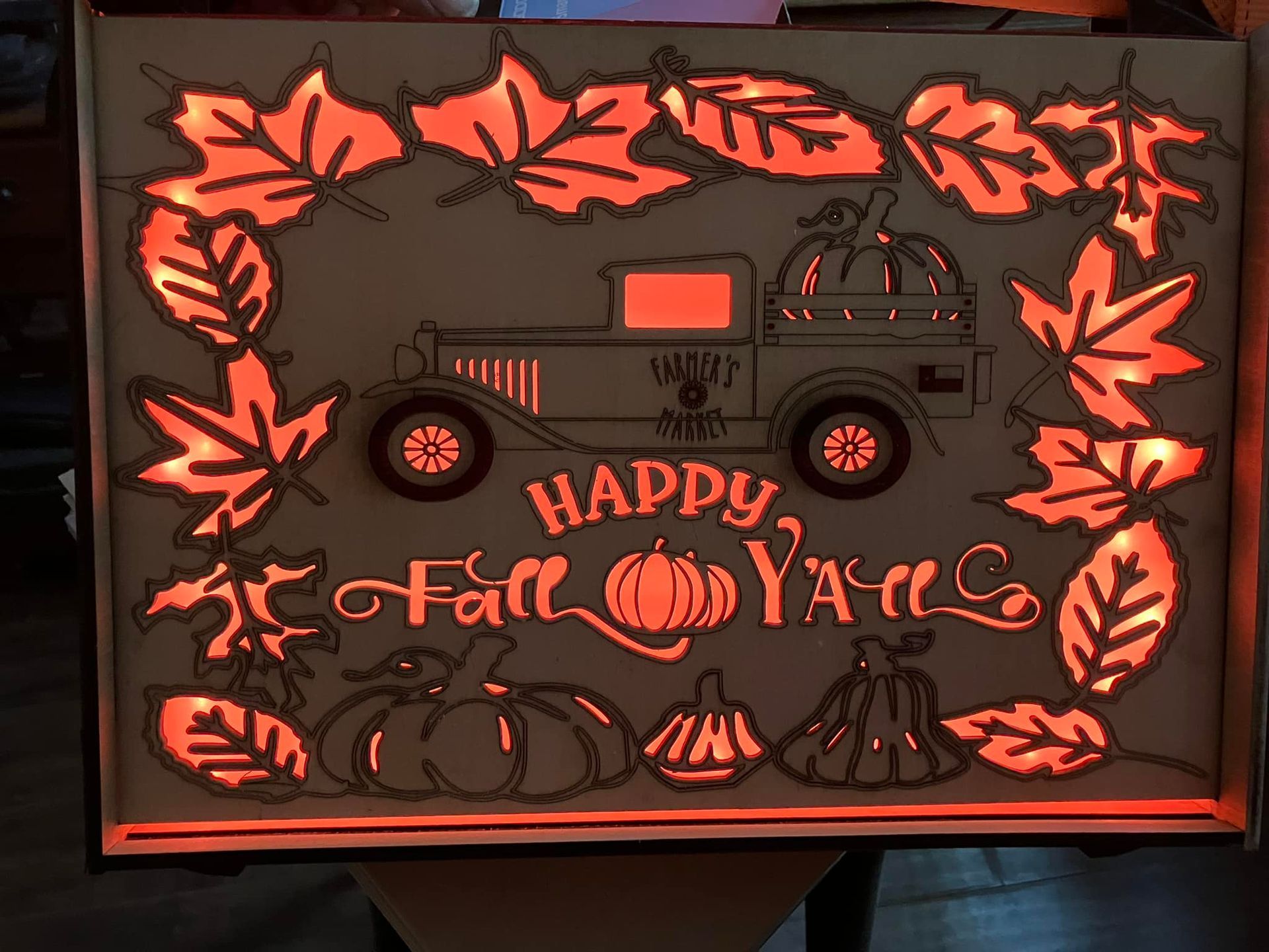 A sign that says happy fall y'all with a truck and pumpkins