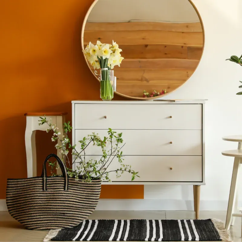 A dresser with a vase of flowers on top of it