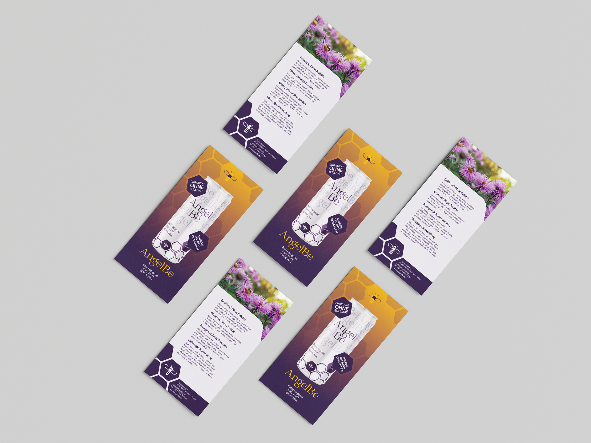 Sechs lila-goldene Broschüren mit floralem Muster und Text lagen verstreut auf einer grauen Fläche.