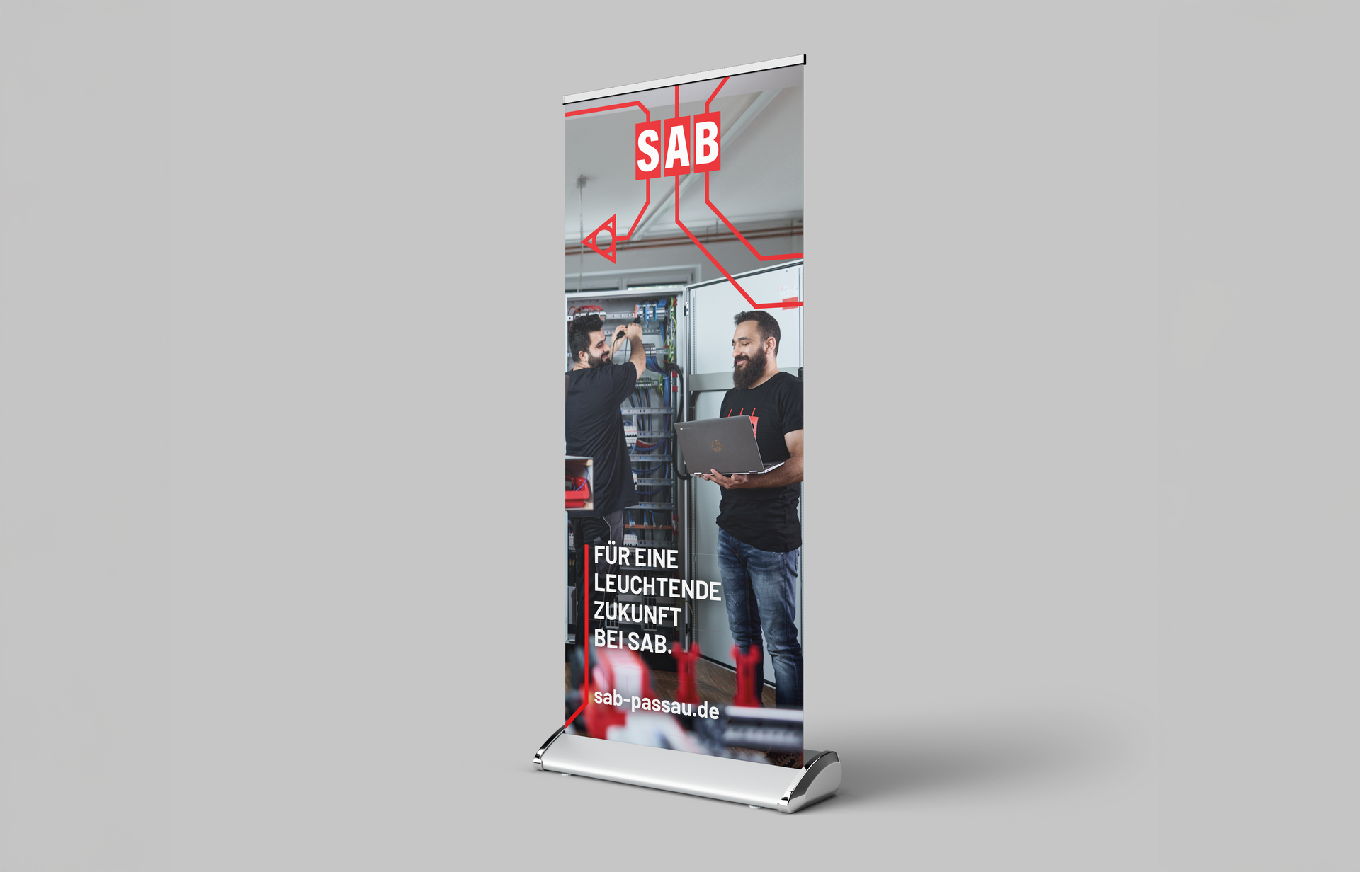 Roll-Up-Banner mit SAB-Logo, zwei Männer arbeiten in einem Serverraum. Rote Linien, weißer Hintergrund, grauer Ständer.