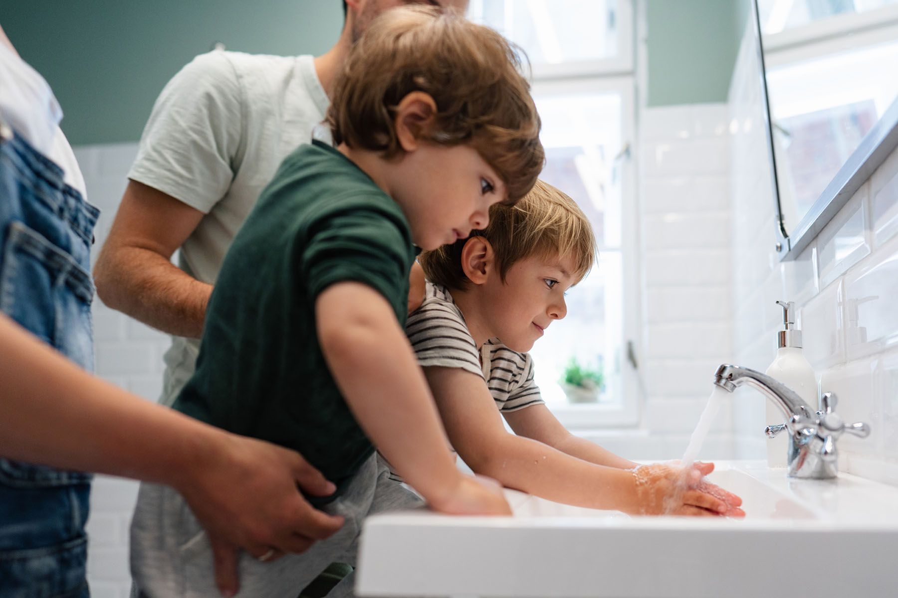 Una famiglia si lava le mani nel lavandino del bagno.