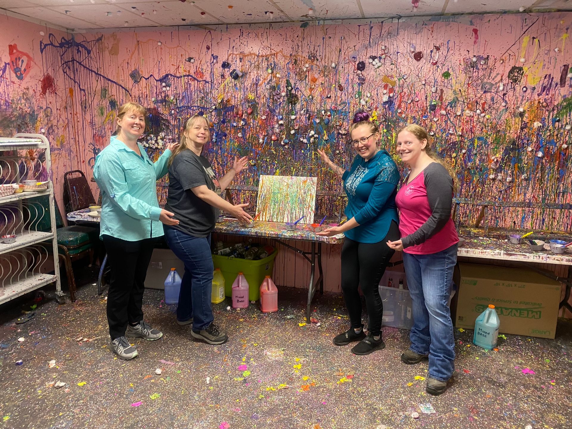 A group of women are standing in front of a wall covered in paint.