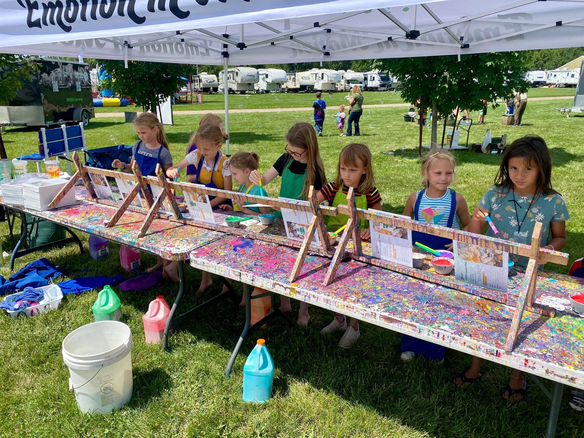 A group of young girls are sitting at a long table painting.