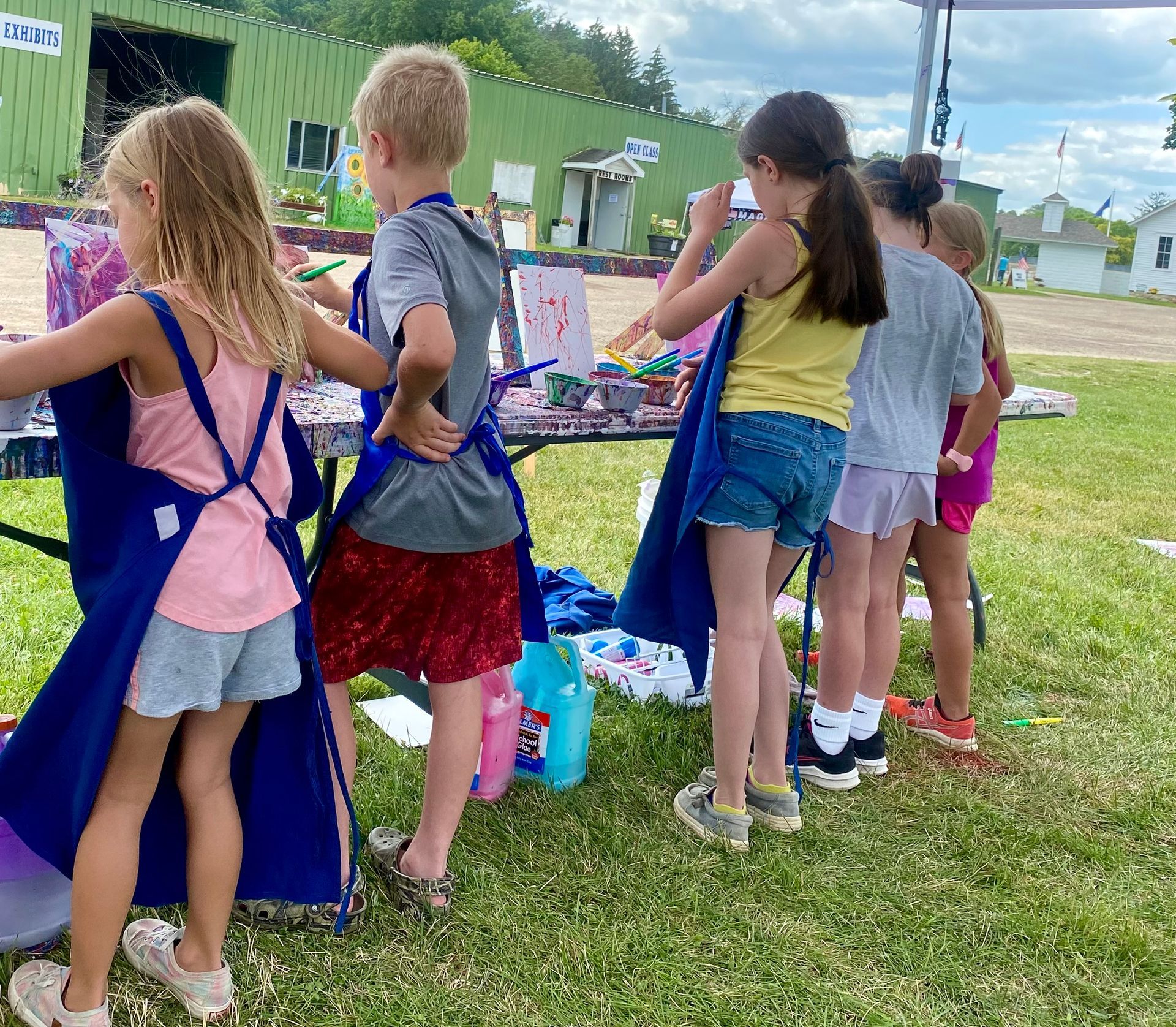 A group of children are standing around a table in a field.