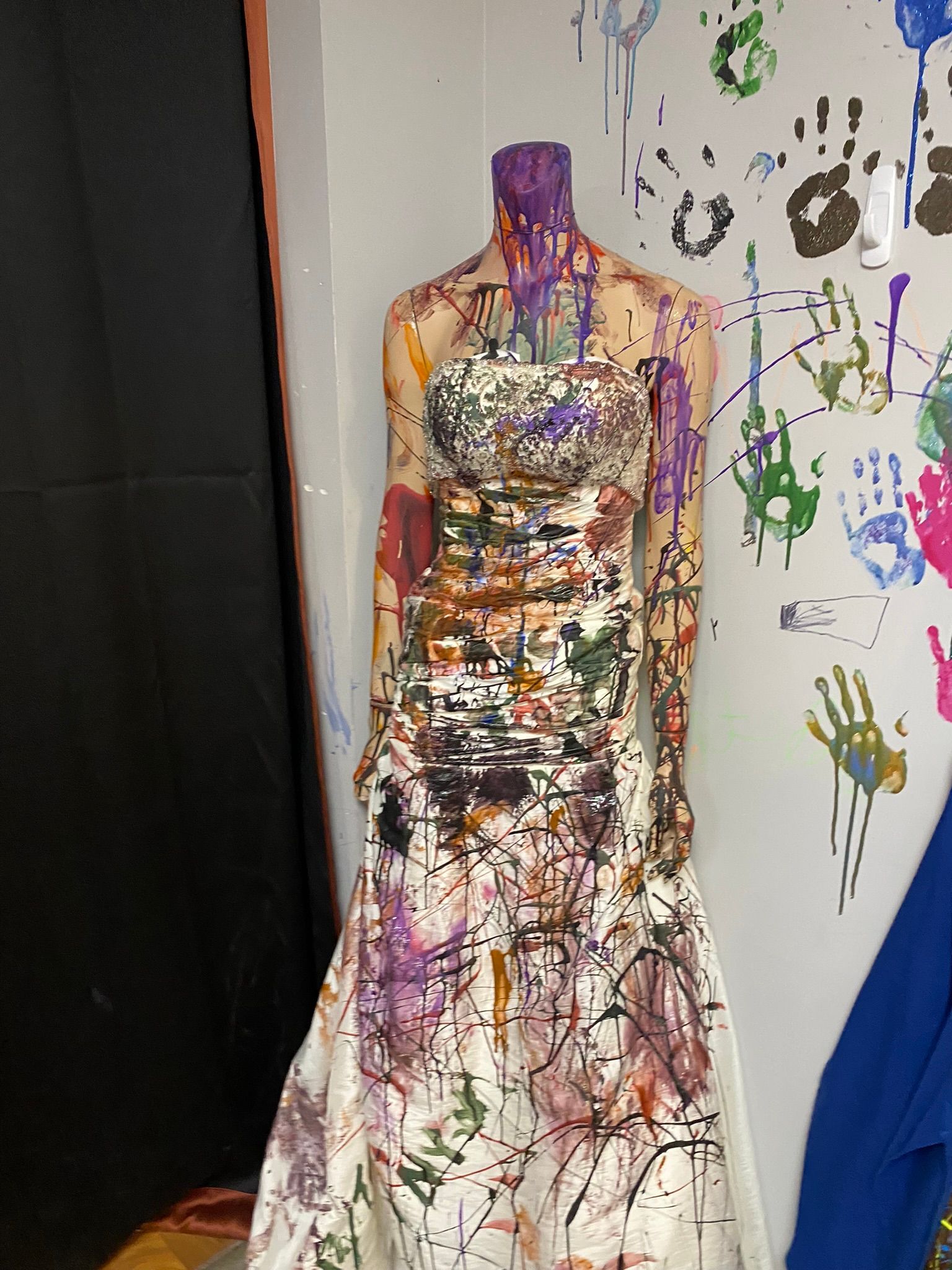 A mannequin in a white dress is covered in paint