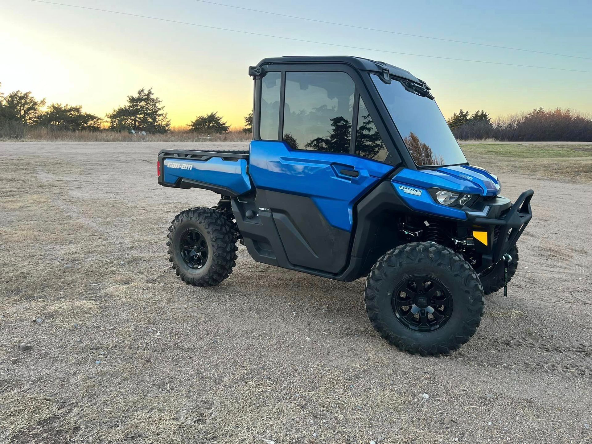 A blue atv is parked in a gravel lot.