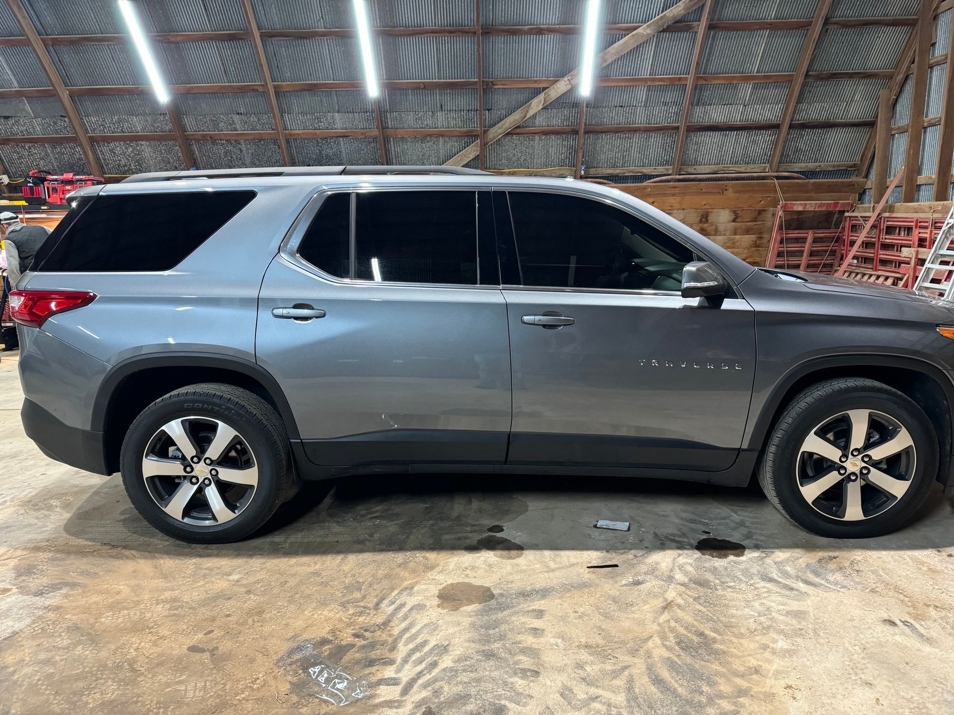 A gray suv is parked in a barn.