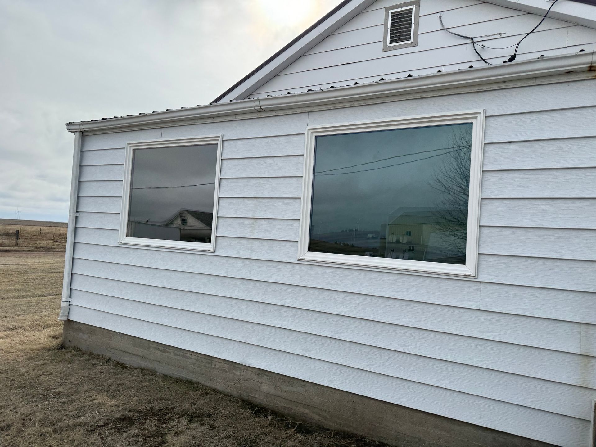 A white house with two windows on the side of it