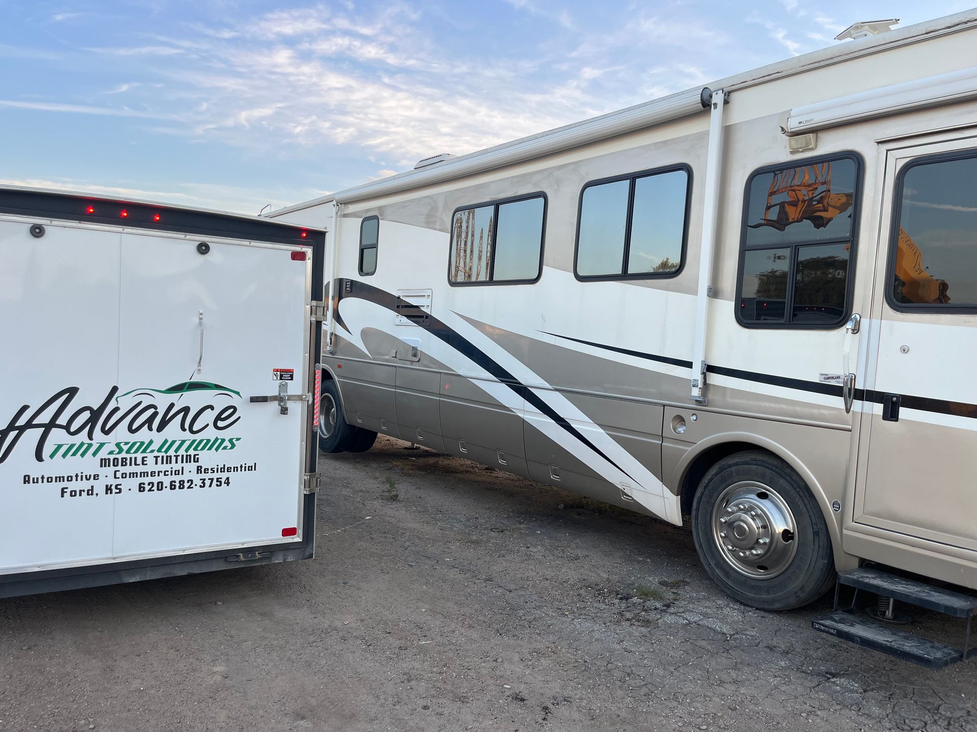 A rv is parked next to a trailer that says advance