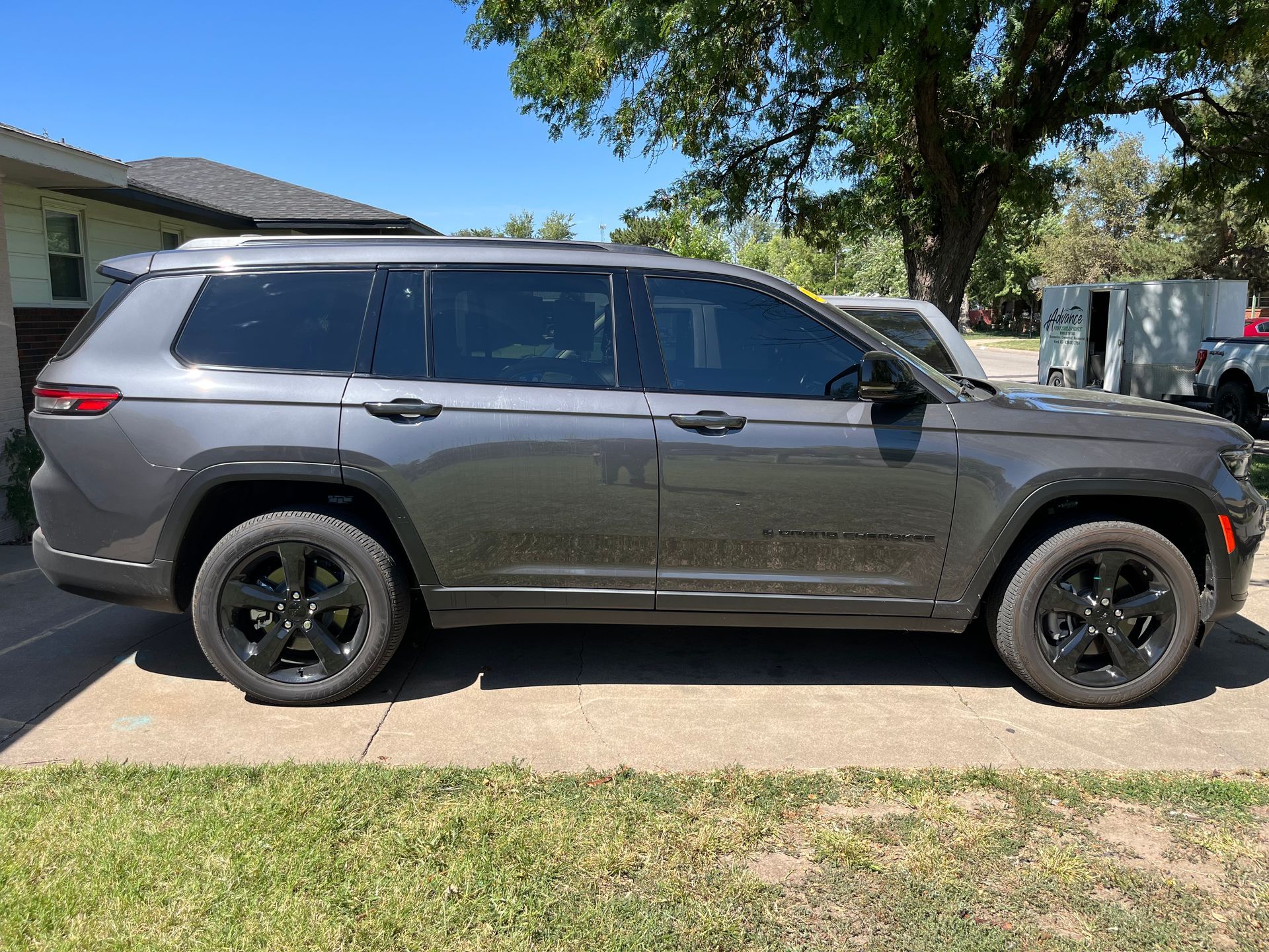A jeep grand cherokee is parked on the side of the road in front of a house.