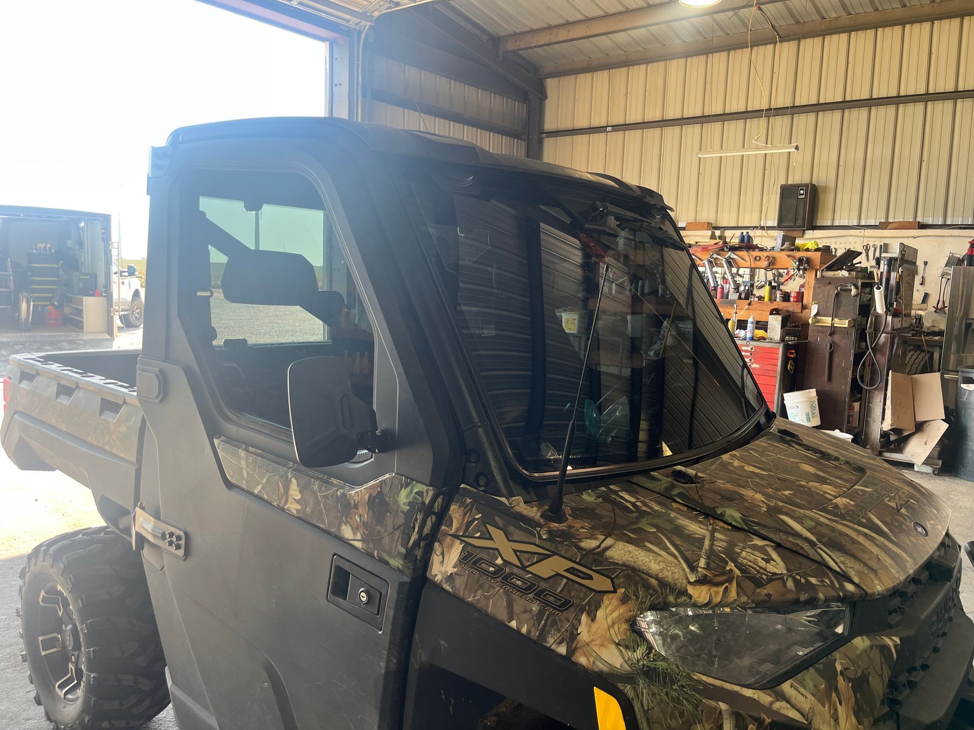 A camouflage truck is parked in a garage.