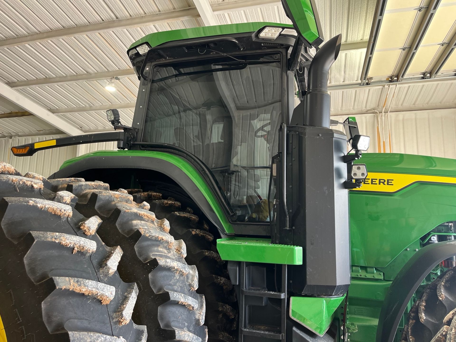 A green and black tractor is parked in a warehouse.