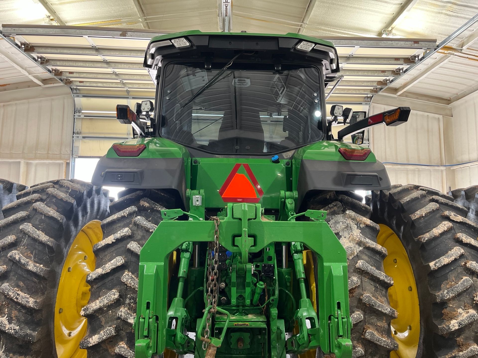 A green john deere tractor is parked in a garage.