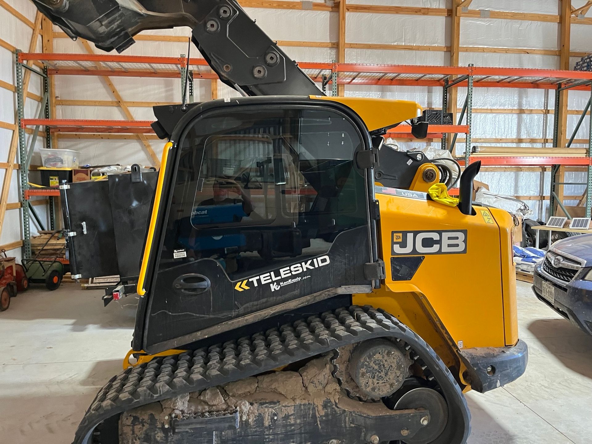 A yellow and black jcb tractor is parked in a garage.