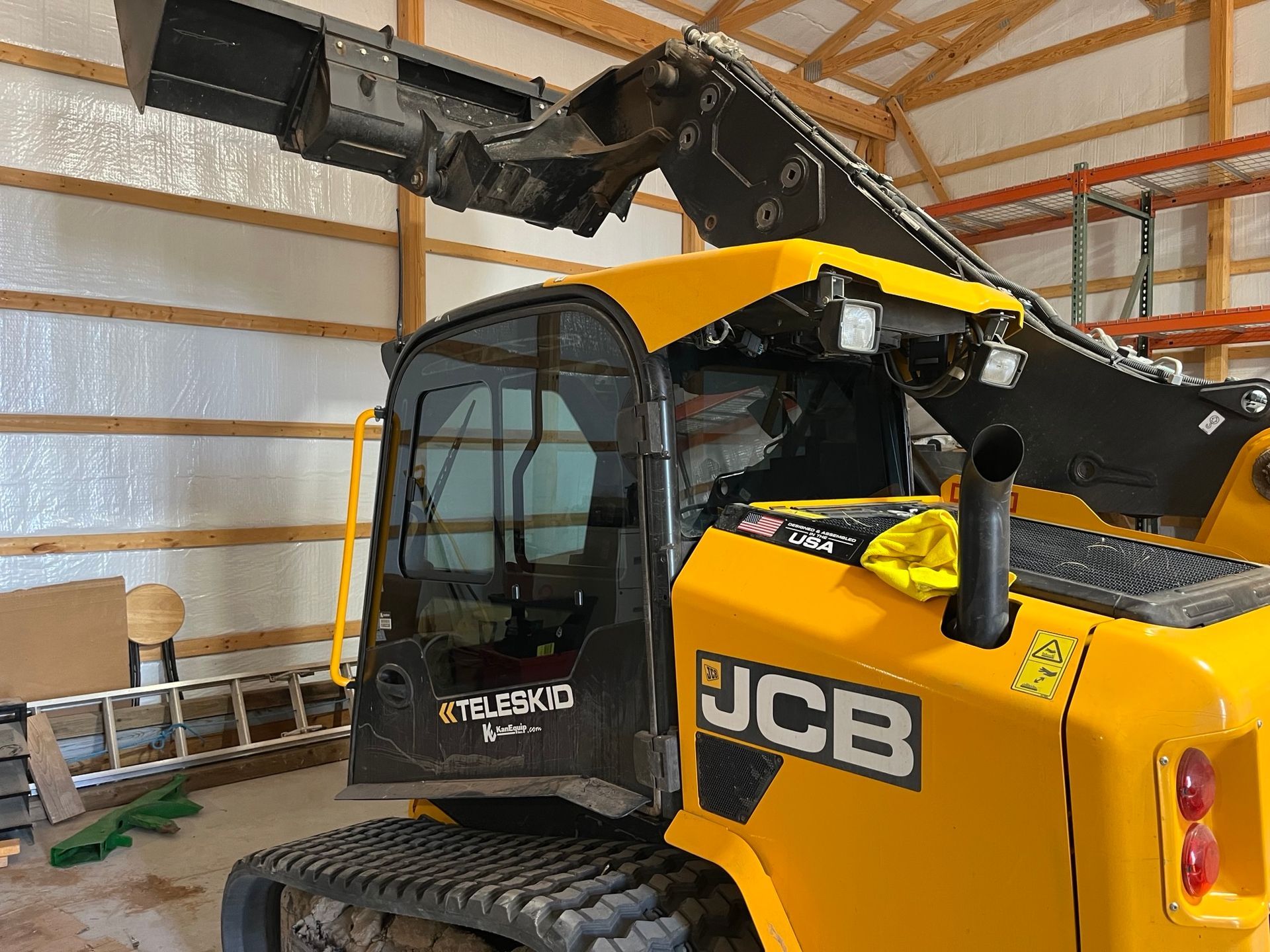 A yellow and black jcb tractor is parked in a barn.
