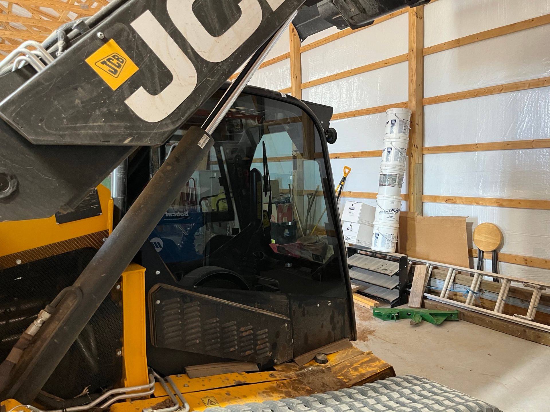 A yellow and black jcb tractor is parked in a garage.
