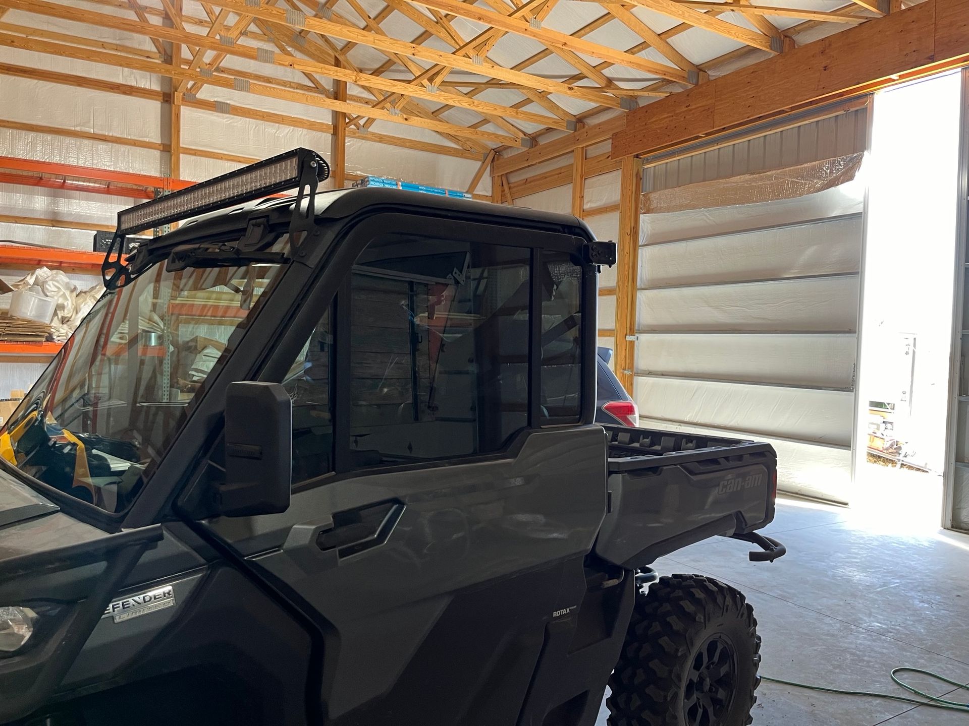 A can am defender is parked in a garage with a light on top of it.
