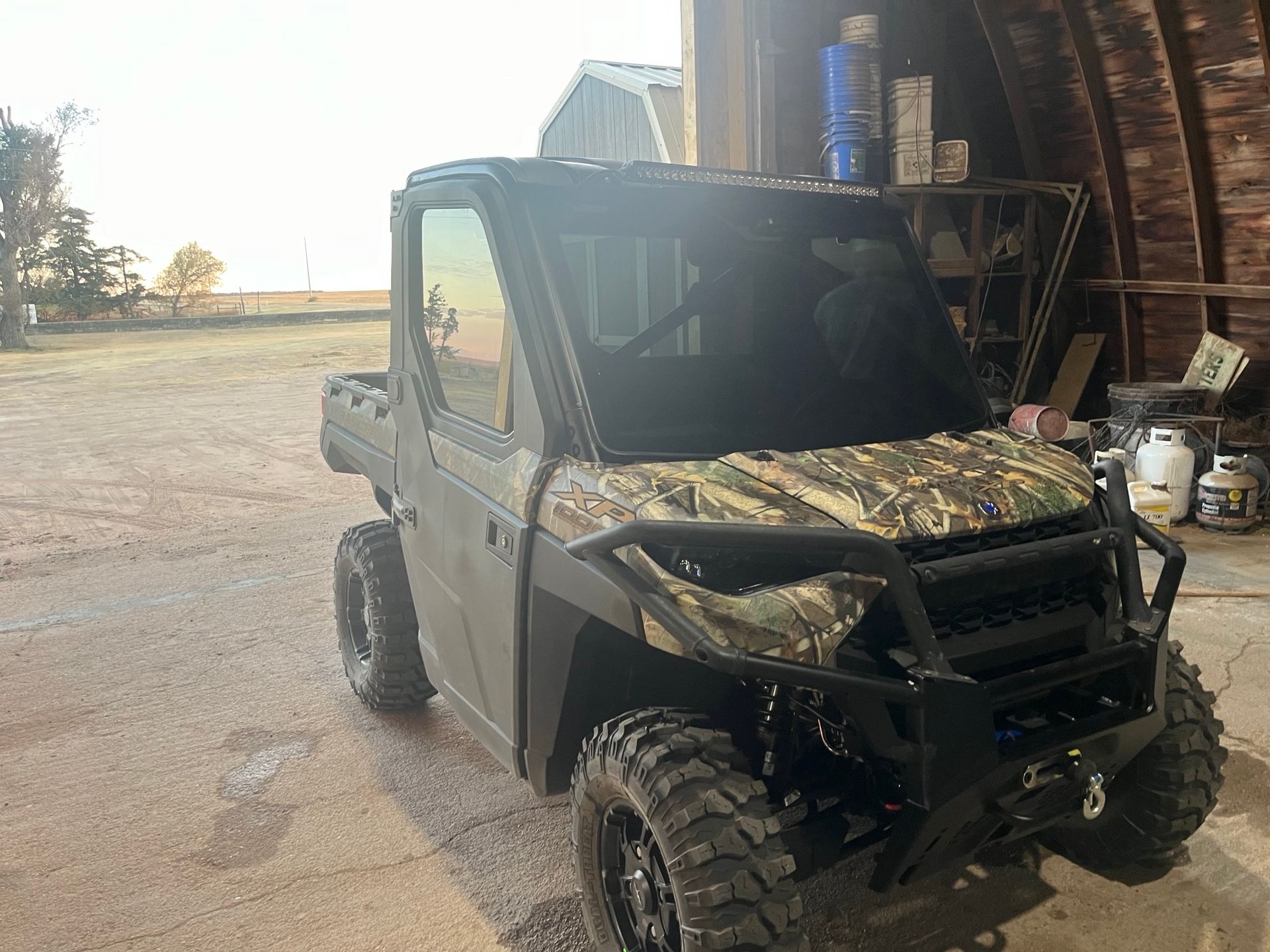 A green atv is parked in front of a barn.