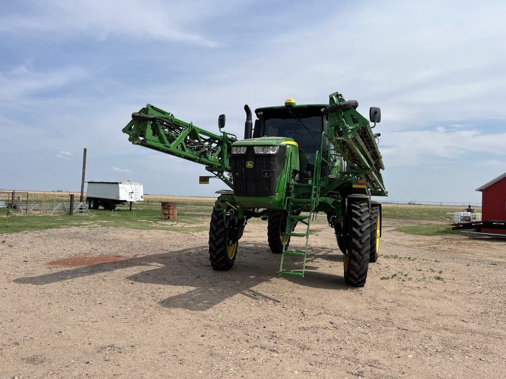A green john deere tractor is parked in a dirt field.