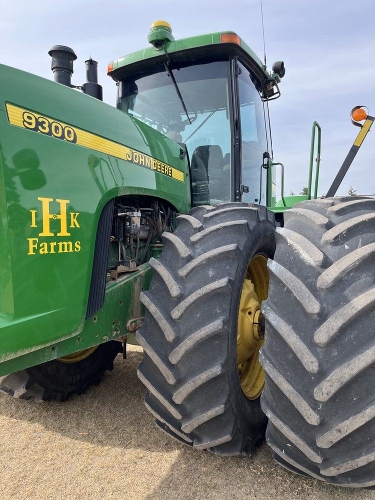 A green john deere tractor is parked in a dirt field.
