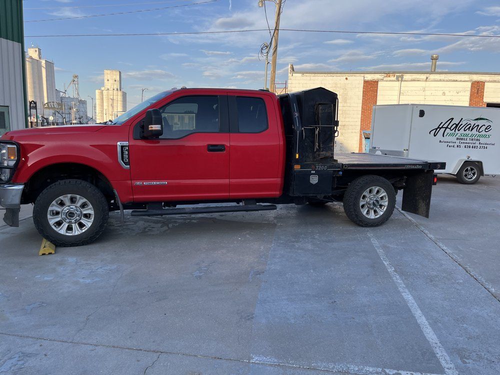A red truck is parked in a parking lot next to a white van.
