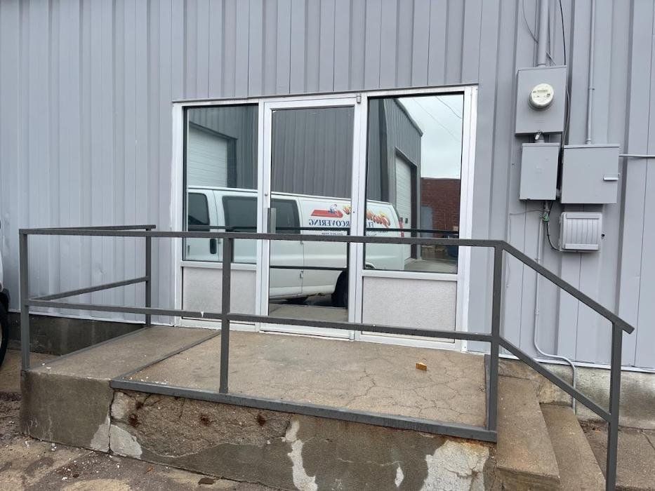 A white van is parked in front of a building with a railing.