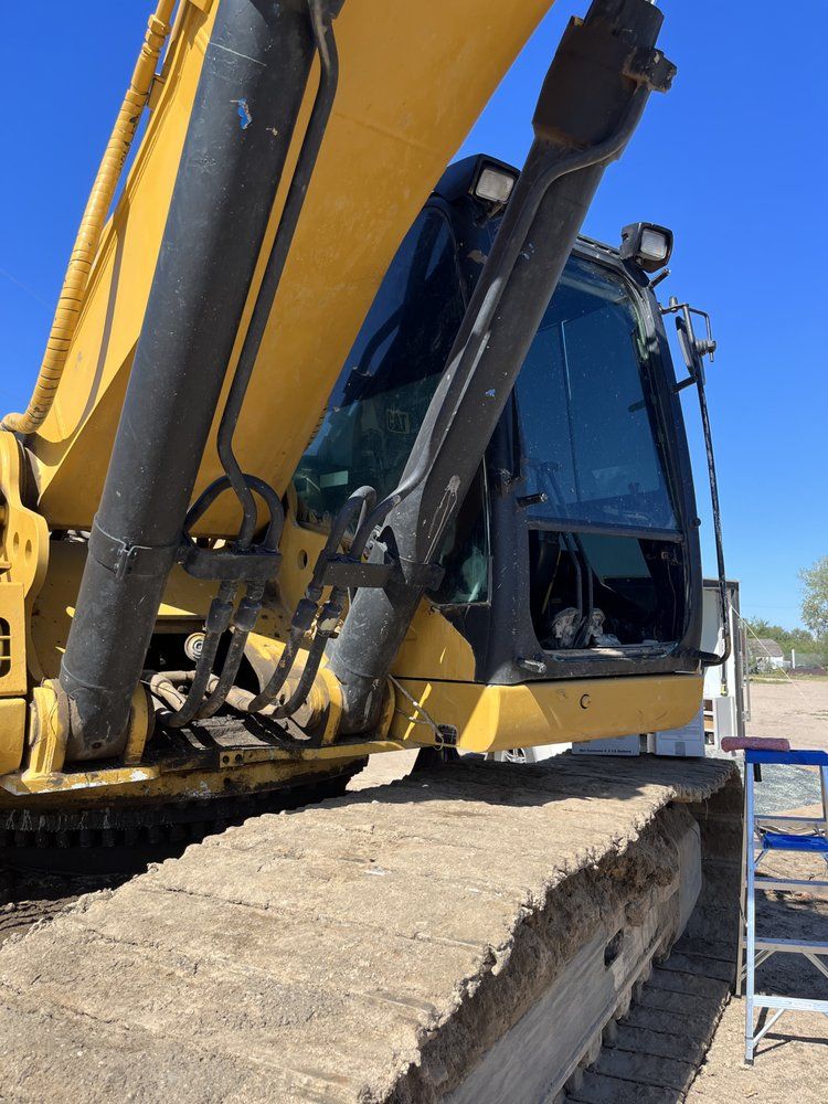 A yellow and black excavator is parked in a dirt field