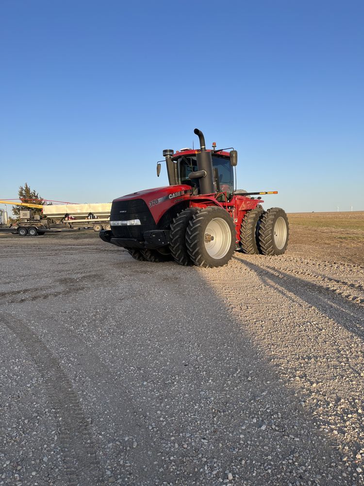 A red tractor is parked on the side of a gravel road.