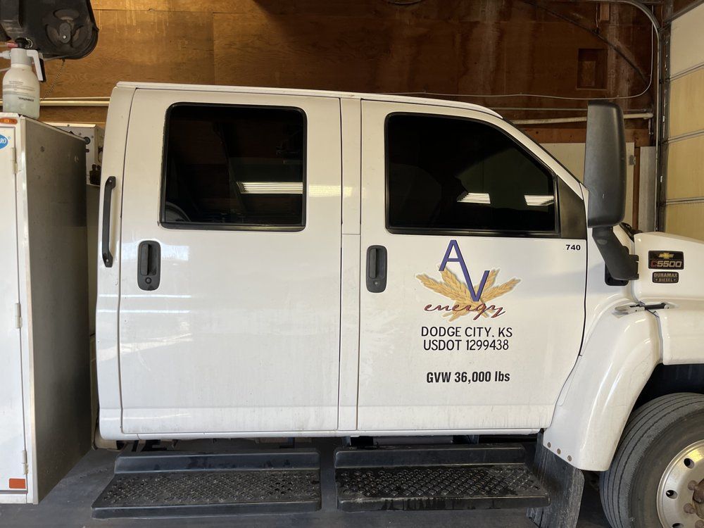 A white truck with the word av on the side is parked in a garage.