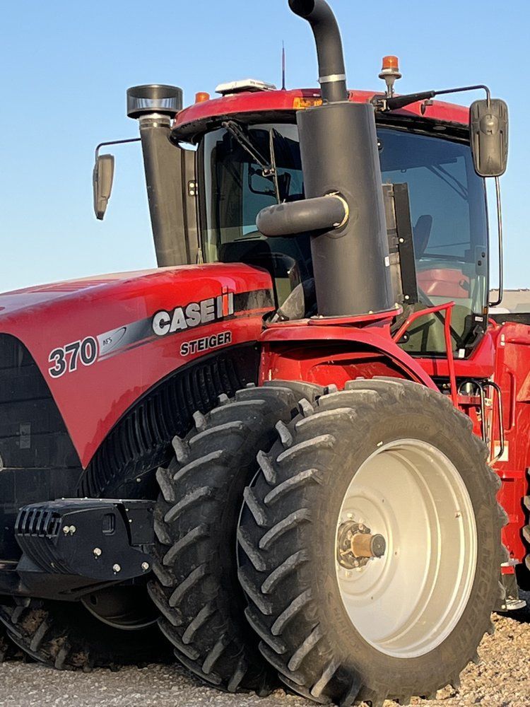 A red case tractor is parked in a dirt field