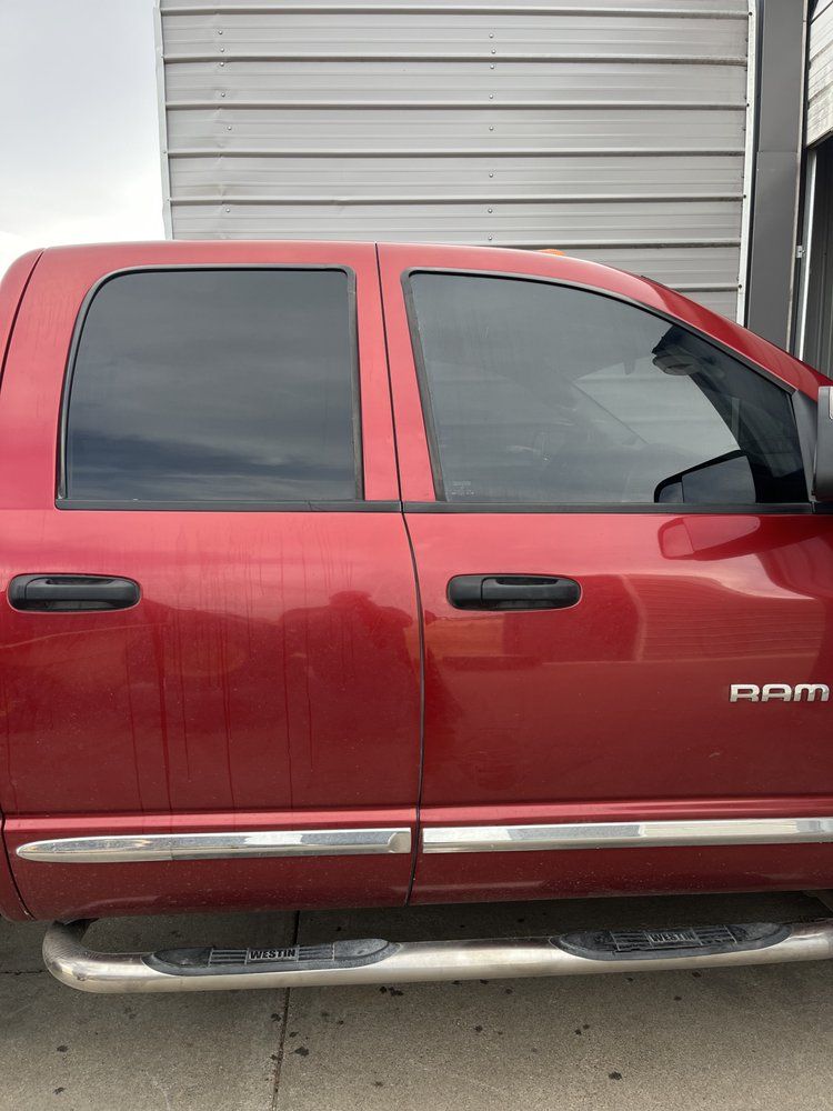 A red dodge ram truck is parked in front of a building.