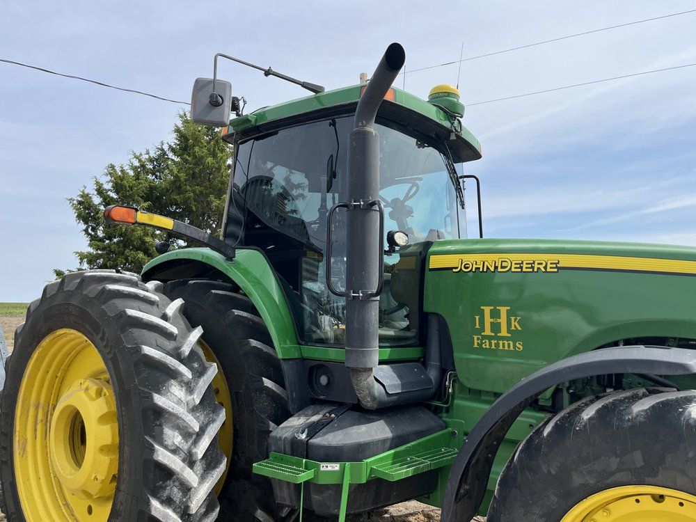 A green and yellow john deere tractor is parked in a field.