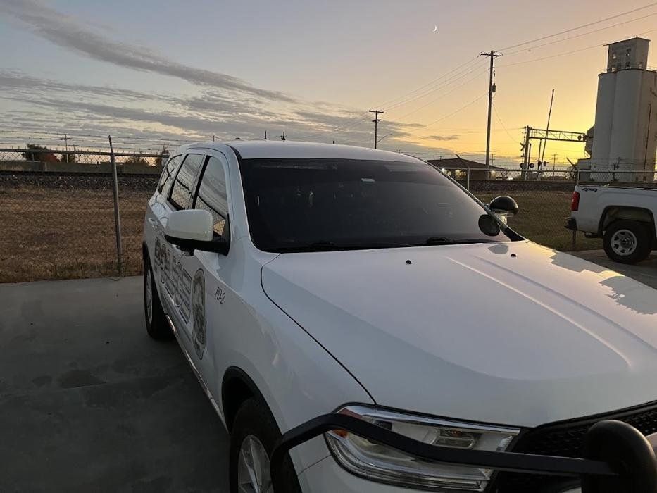 A white car is parked in a parking lot at sunset.