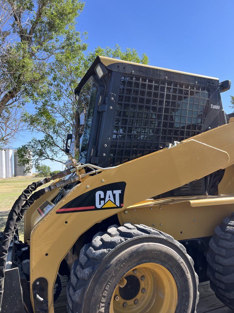 A cat skid steer is parked on a wooden deck.