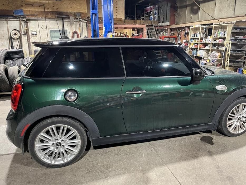 A green mini cooper is parked in a garage.
