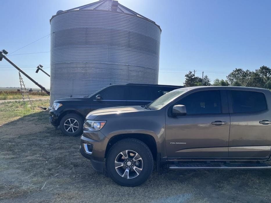 Two trucks are parked next to each other in front of a silo.