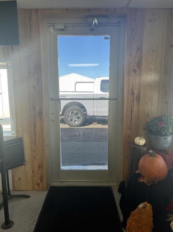 A truck is parked in a parking lot behind a glass door.