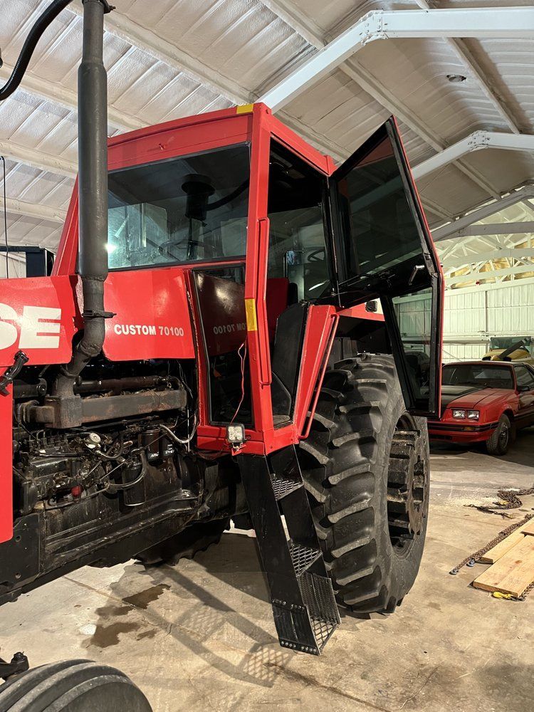 A red tractor is parked in a garage with its doors open.