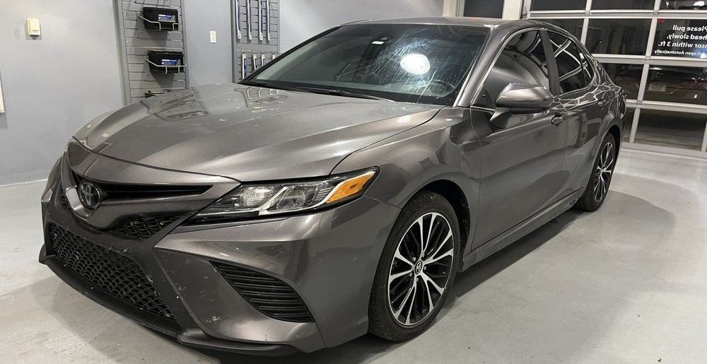 A gray toyota camry is parked in a garage.